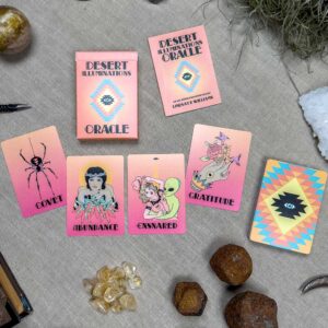 The "Desert Illuminations Oracle - 1st Edition" set is displayed on a surface, showcasing colorful designs of a spider, woman, coiled snake, and geometric patterns. Surrounding the cards are artfully arranged crystals and stones.