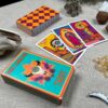 The Desert Illuminations Tarot - 1st Edition is displayed on a table. Three drawn cards showcase its colorful, mystical designs, while crystals and natural objects are artistically scattered around.