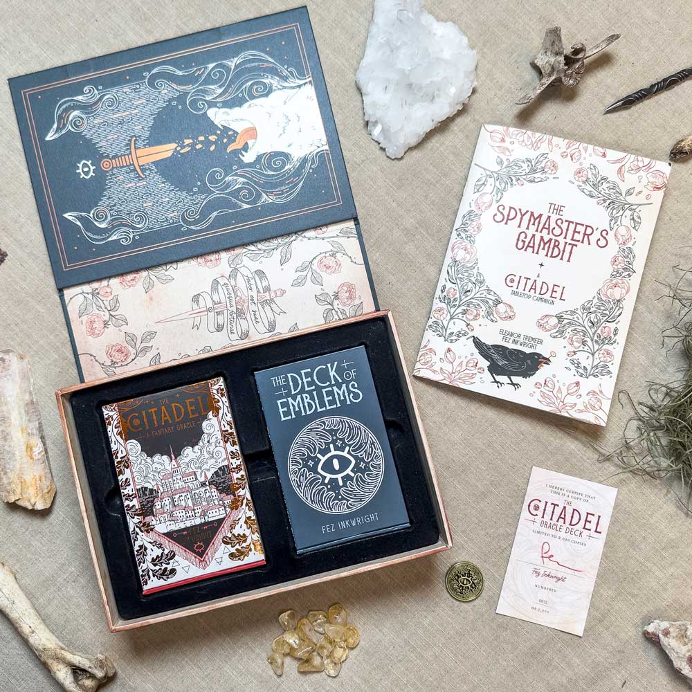 Displayed elegantly, the set showcases "The Spymaster's Gambit" box and book, "The Deck of Emblems" cards, an instruction booklet, stones, crystals, and features the exclusive Citadel Oracle - LE Boxed Set.