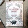 Cover of "The Spymaster's Gambit + A Citadel Tabletop Campaign" by Eleanor Tremeer and Fez Inkwright features ornate floral and vine designs with a black bird at the bottom, reminiscent of The Citadel Oracle - LE Boxed Set. Placed on a textured surface.