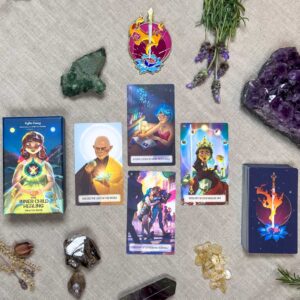 A vibrant oracle spread decorates a beige surface with crystals, dried herbs, and stones. The Inner Child Healing Oracle deck box sits to the left, displaying an illustration. Centered at the top is a circular card adorned with a sword and flower.