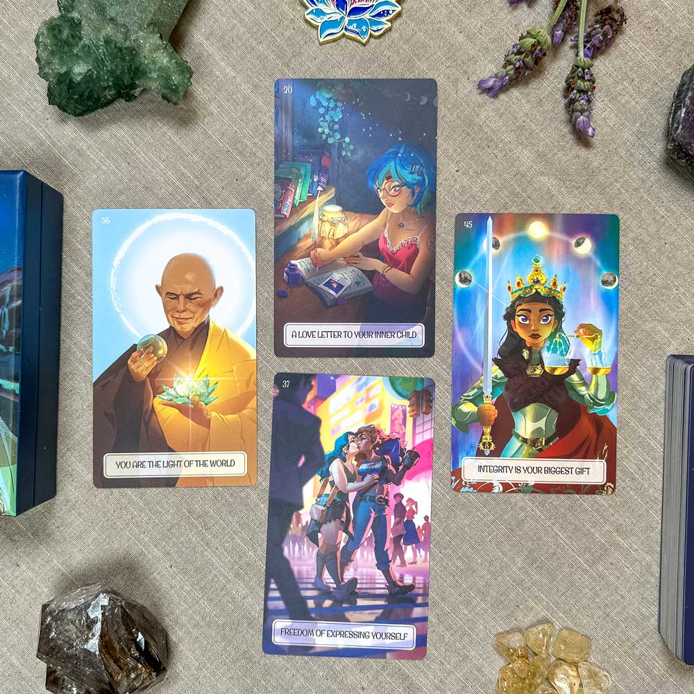 A set of four colorful cards from The Inner Child Healing Oracle sits on a table. Each card features unique art: a bald man with light, a woman at a desk, a crowned girl with lights, and an urban scene, surrounded by crystals and plants.