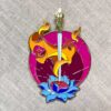 Enamel pin depicting a sword piercing a blue lotus, encircled by vibrant orange-yellow flames, set against a purplish circular backdrop, inspired by The Inner Child Healing Oracle.