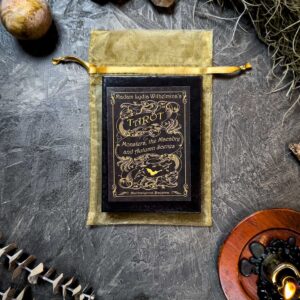 The "Madam Lydia Wilhelmina's Tarot" deck is elegantly displayed on a golden pouch surrounded by moss, a candle, and decorative items, perfectly capturing the mystical ambiance the tarot is renowned for.
