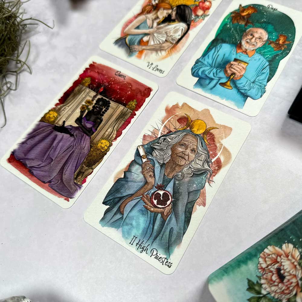 The Unfolding Path Tarot deck is laid out on a surface, featuring "The High Priestess" card with an elderly figure holding a heart-shaped object, surrounded by vividly illustrated cards.