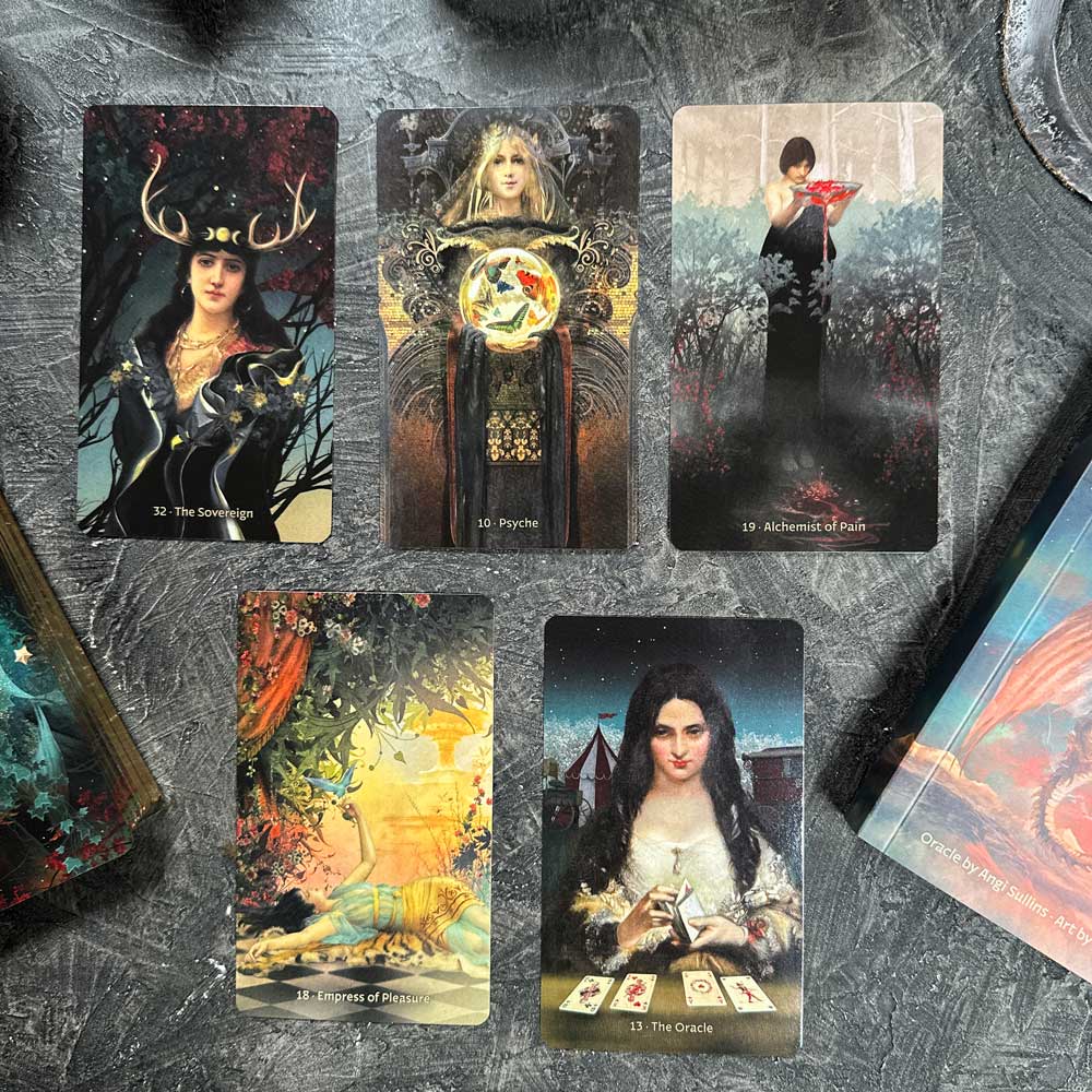 Five oracle cards with intricate mystical artwork and symbols lie on a textured dark surface, next to the W.I.T.C.H. guidebook hinting at secrets to be unveiled.