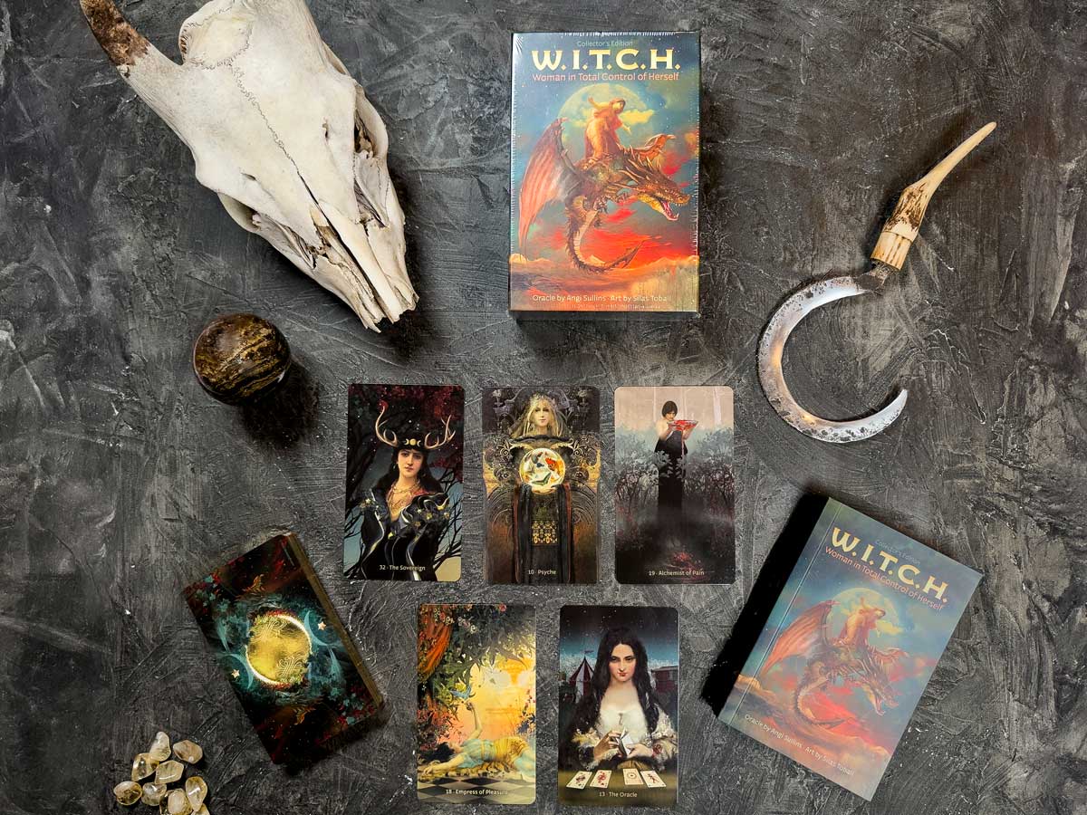 The W.I.T.C.H. mystical set includes oracle cards with enchanting fantasy artwork, a labeled box, goat skull, antler-handled sickle, small bones, and a sphere against a dark background.